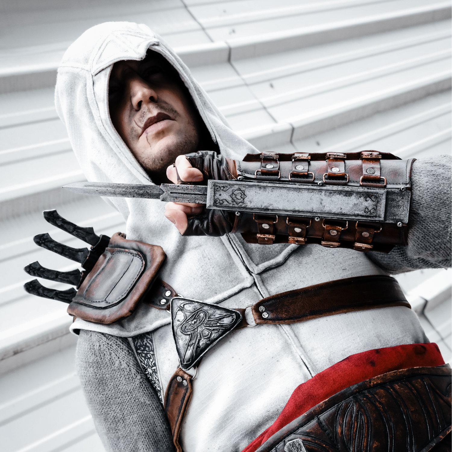 Person in Assassin's Creed Altair costume with a hidden blade against a white background